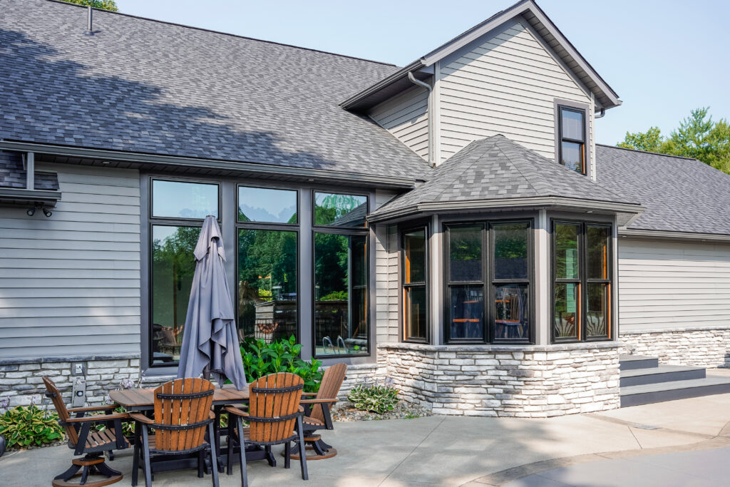 The back of a home featuring a number of black double hung and picture windows