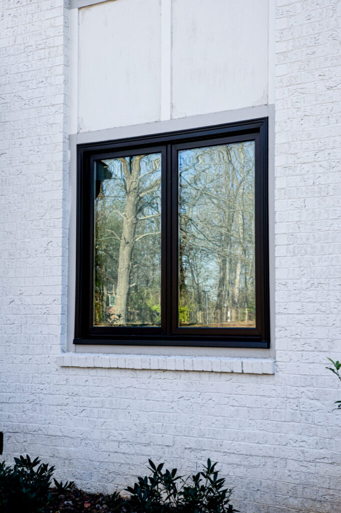 Black casement windows on the side of a white brick home.