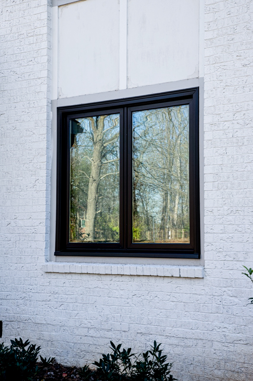 2-lite black casement window on a white brick home.