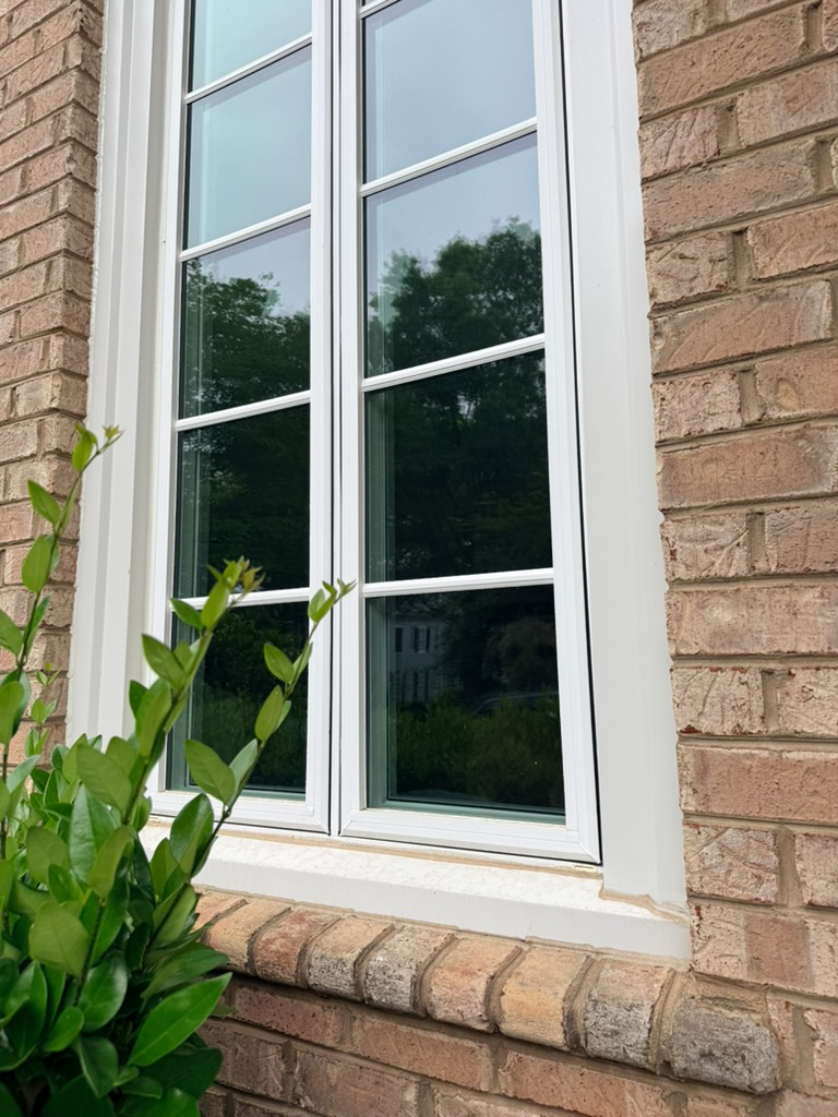 White casement window on a brick home.