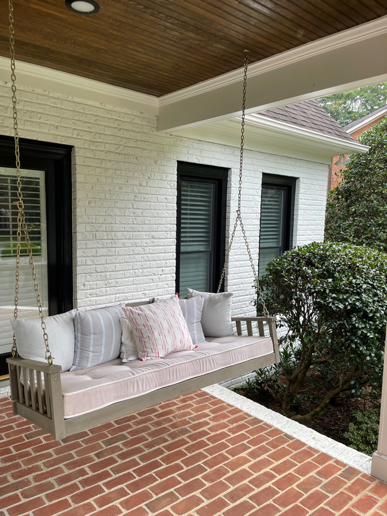 Double-hung black windows with porch swing in front.