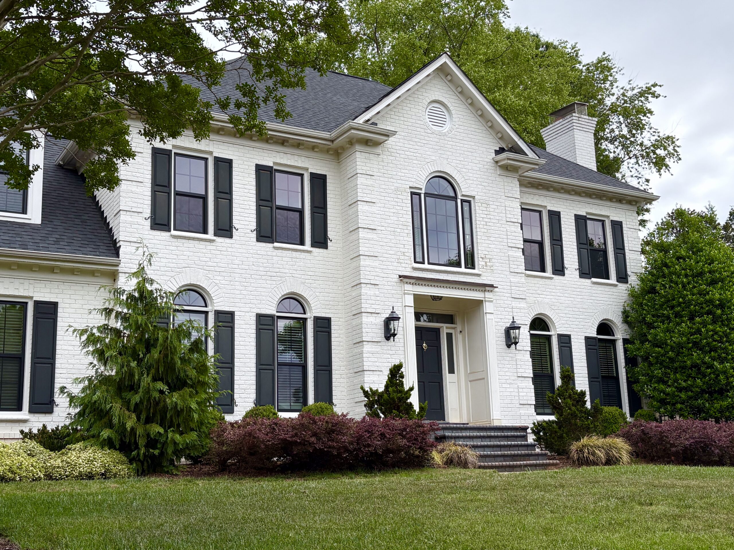 Wide view of white brick home with double-hung, picture, and specialty windows.