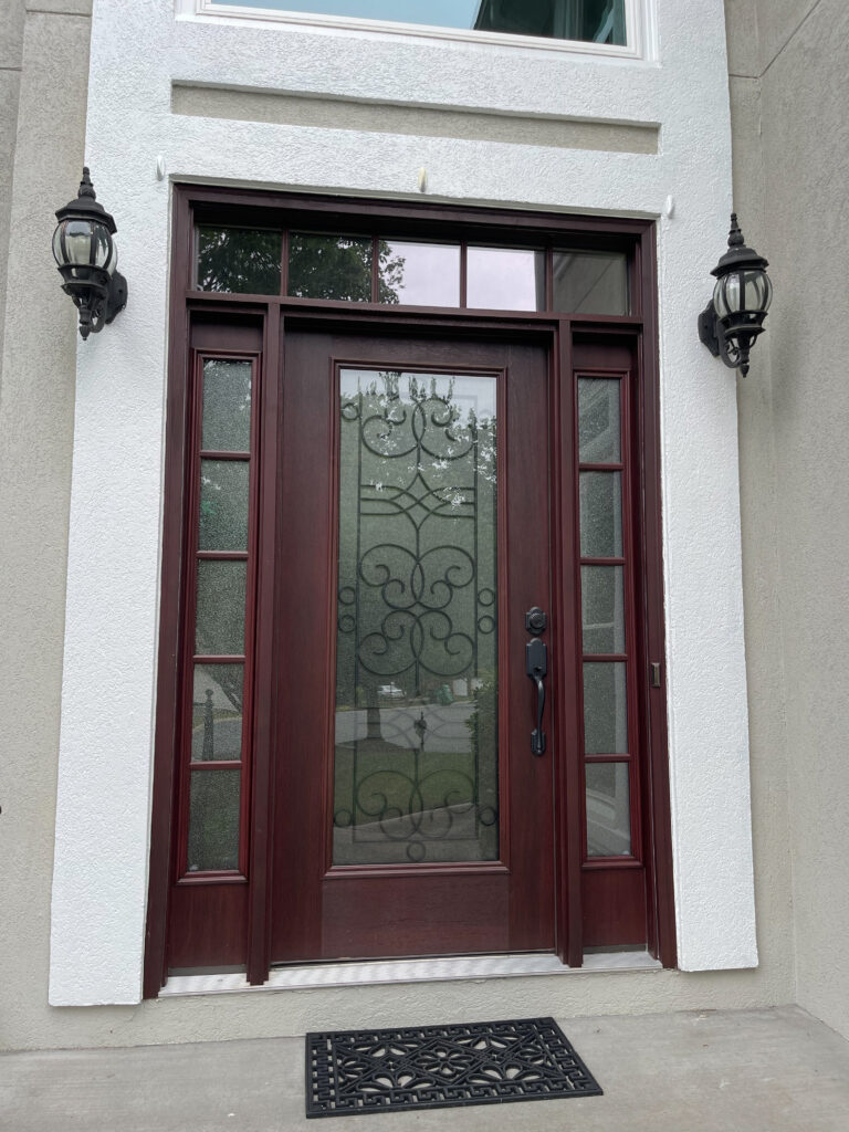 Maroon entry door with wrought iron glass.