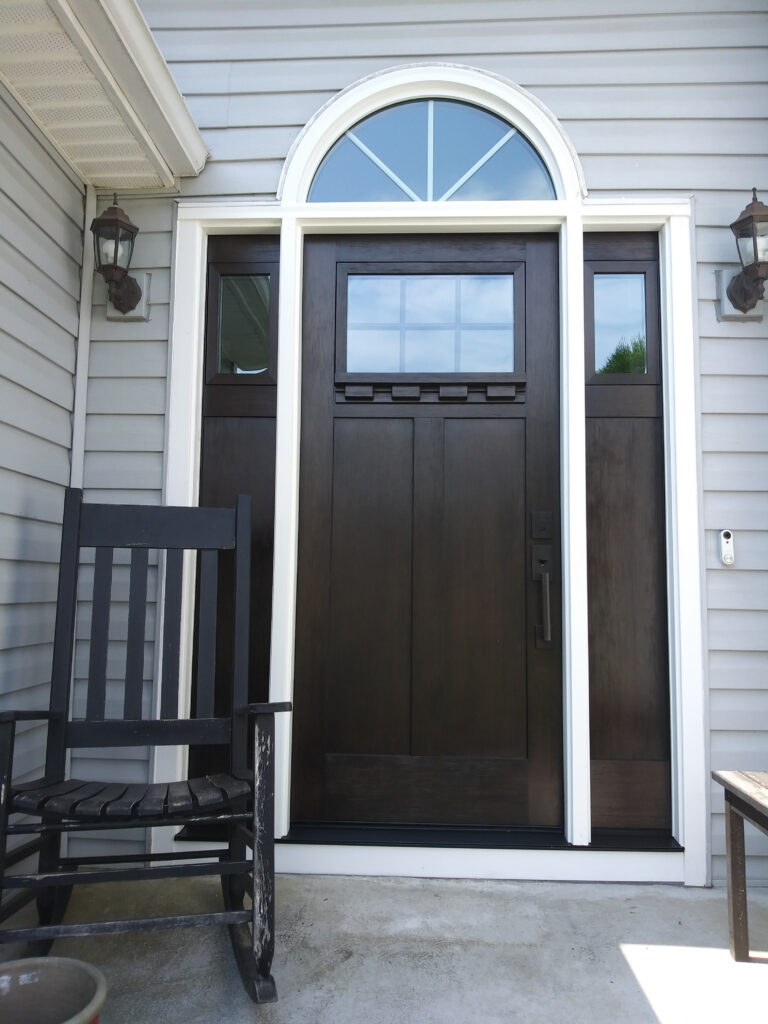 Dark brown entry door with arched window.