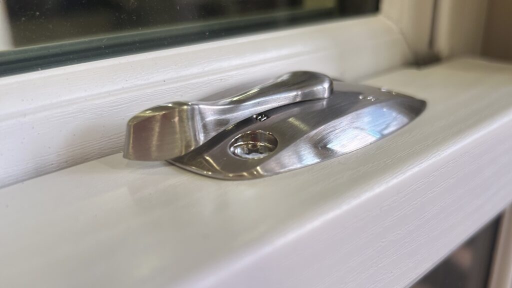 Close up of satin nickel hardware of a white window.