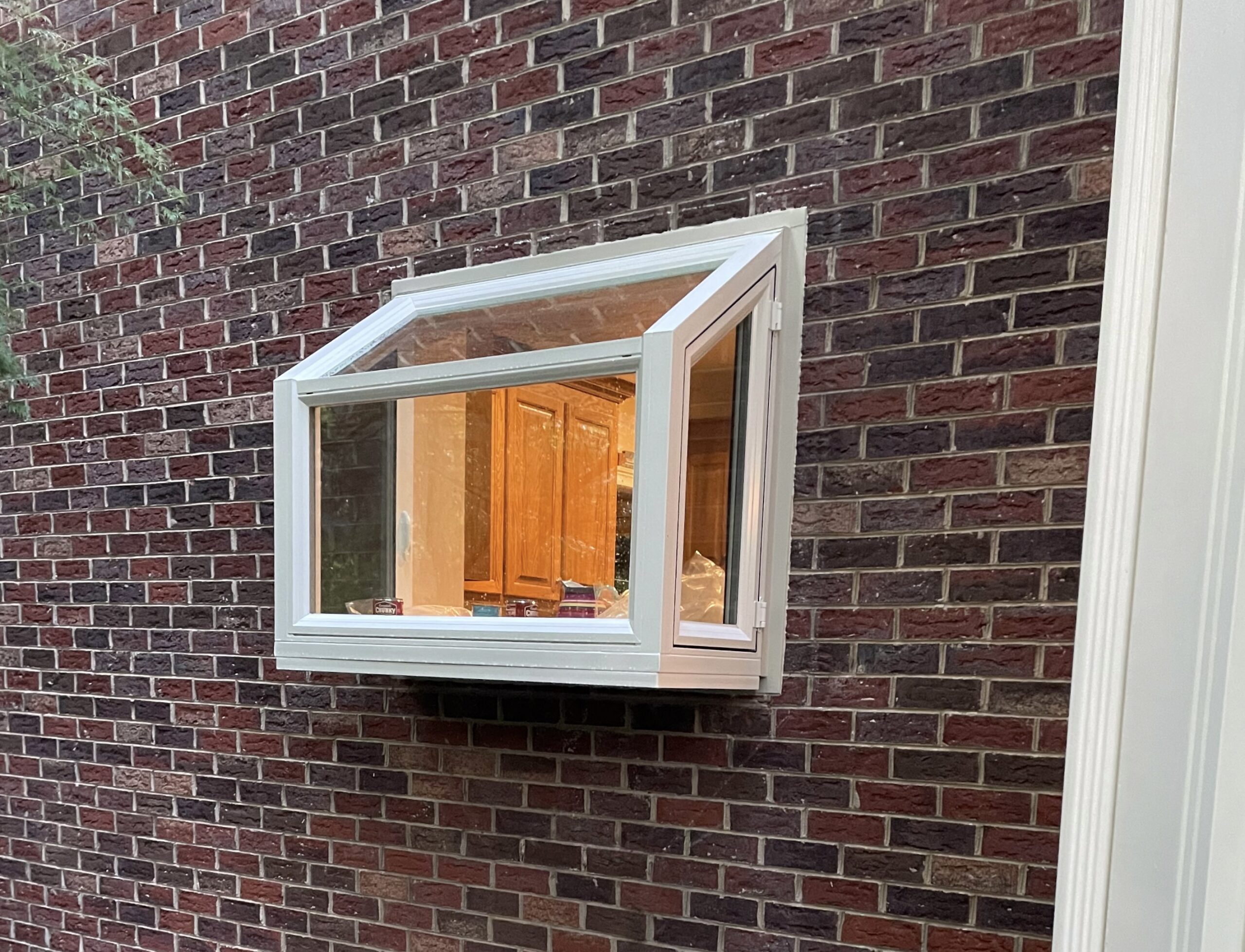 Garden window from exterior with light on.