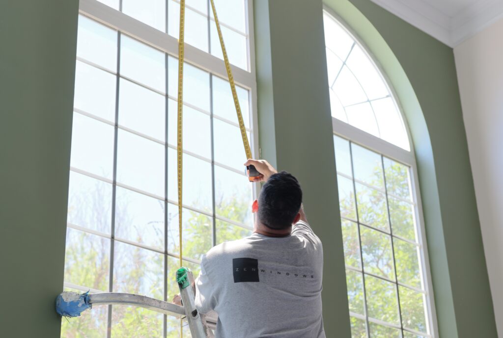 Zen Windows employee measuring tall picture window.