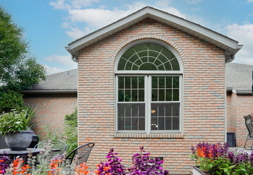 Half-round sandstone window with sunburst grids.