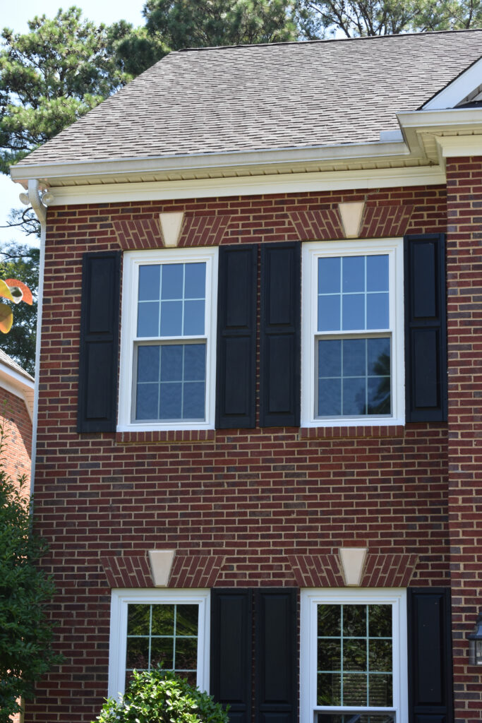 White double-hung windows with colonial grids on a red brick house.