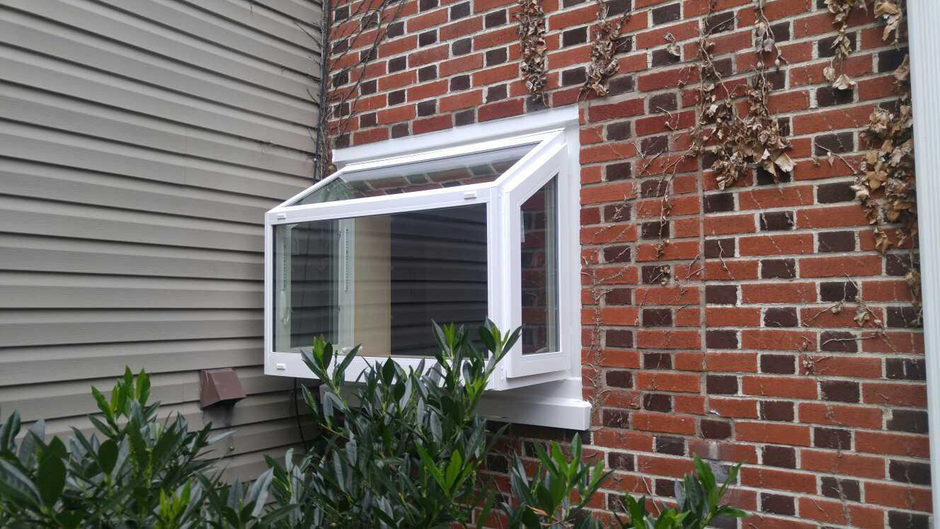 White garden window from exterior of brick house.