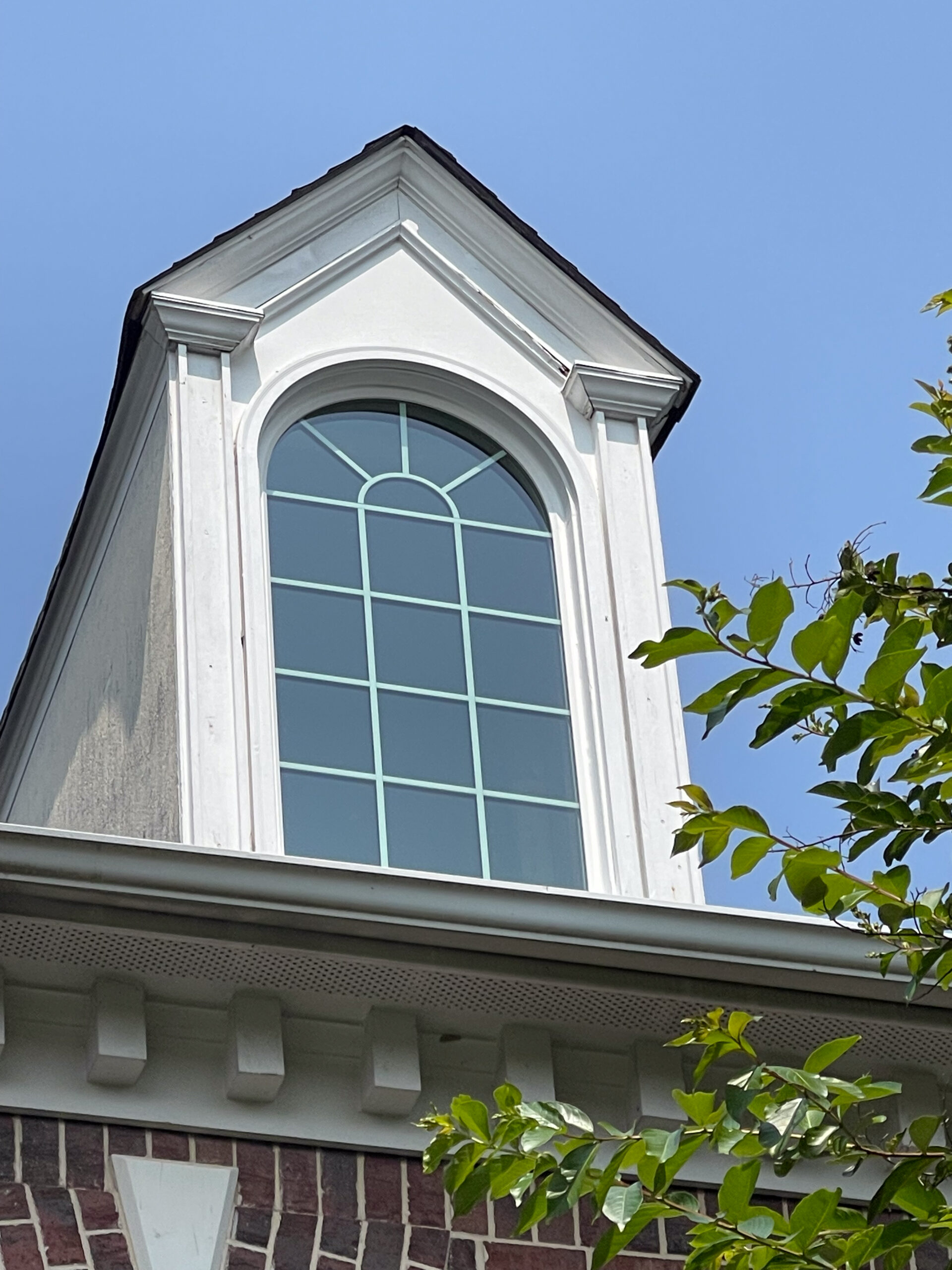 White round top window with sunburst grids in attic.
